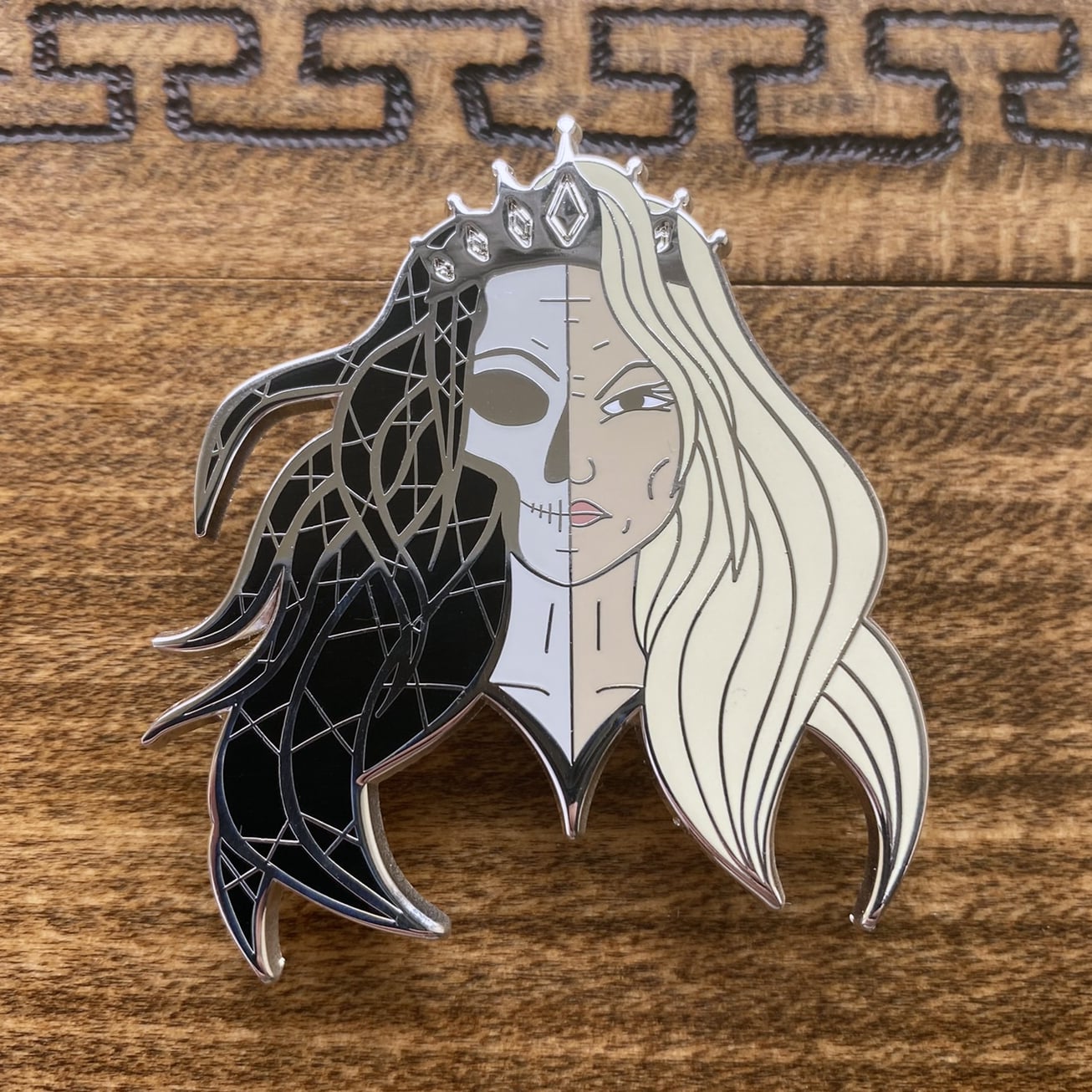 Silver-plated enamel pin of the Norse god Hel. The pin depicts the icon as half corpse and half alive.