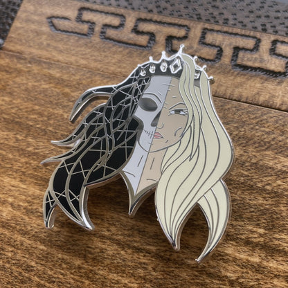 Silver-plated enamel pin of the Norse god Hel. The pin depicts the icon as half corpse and half alive. Angle shows off the sliver-plating.