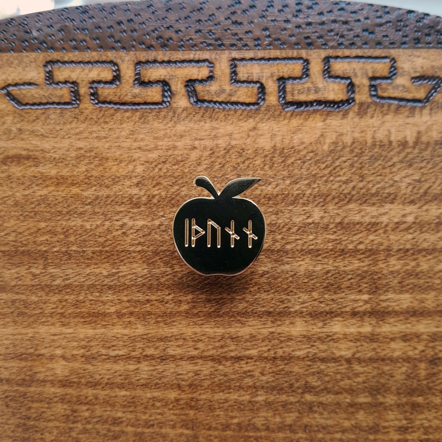 Enamel pin of Idunn's golden apple. Engraved on the apple is the word idunn in younger futhark. 