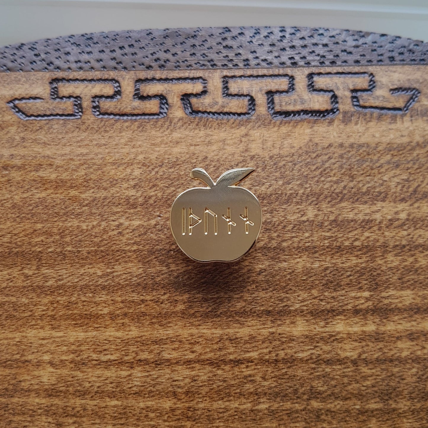 Enamel pin of Idunn's golden apple. Engraved on the apple is the word idunn in younger futhark.