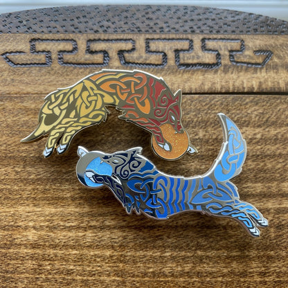 Enamel pin of Skoll the wolf and Hati the wolf. Both pins contain knotwork and multiple shades of blue for Hati and red for Skoll