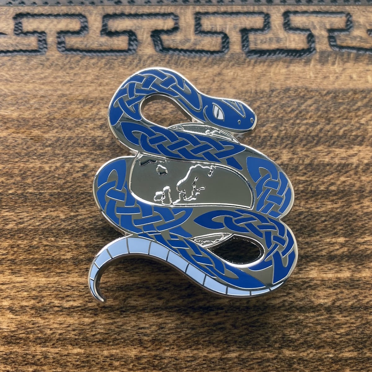 Silver-plated enamel pin of Jormungandr the Norse icon know as the Midgard serpent. The pin contains knotwork and depicts the snake circling the world. 