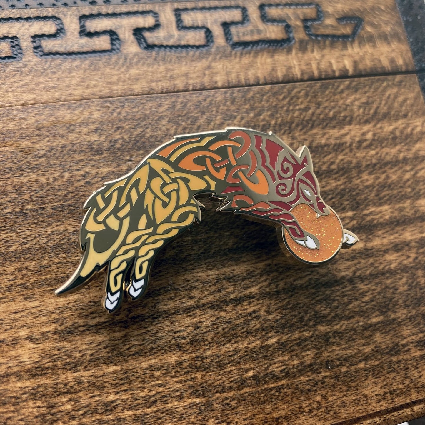 Gold-plated enamel pin of Skoll the Norse icon. The pin is a wolf and contains knotwork and multiple shades of red.