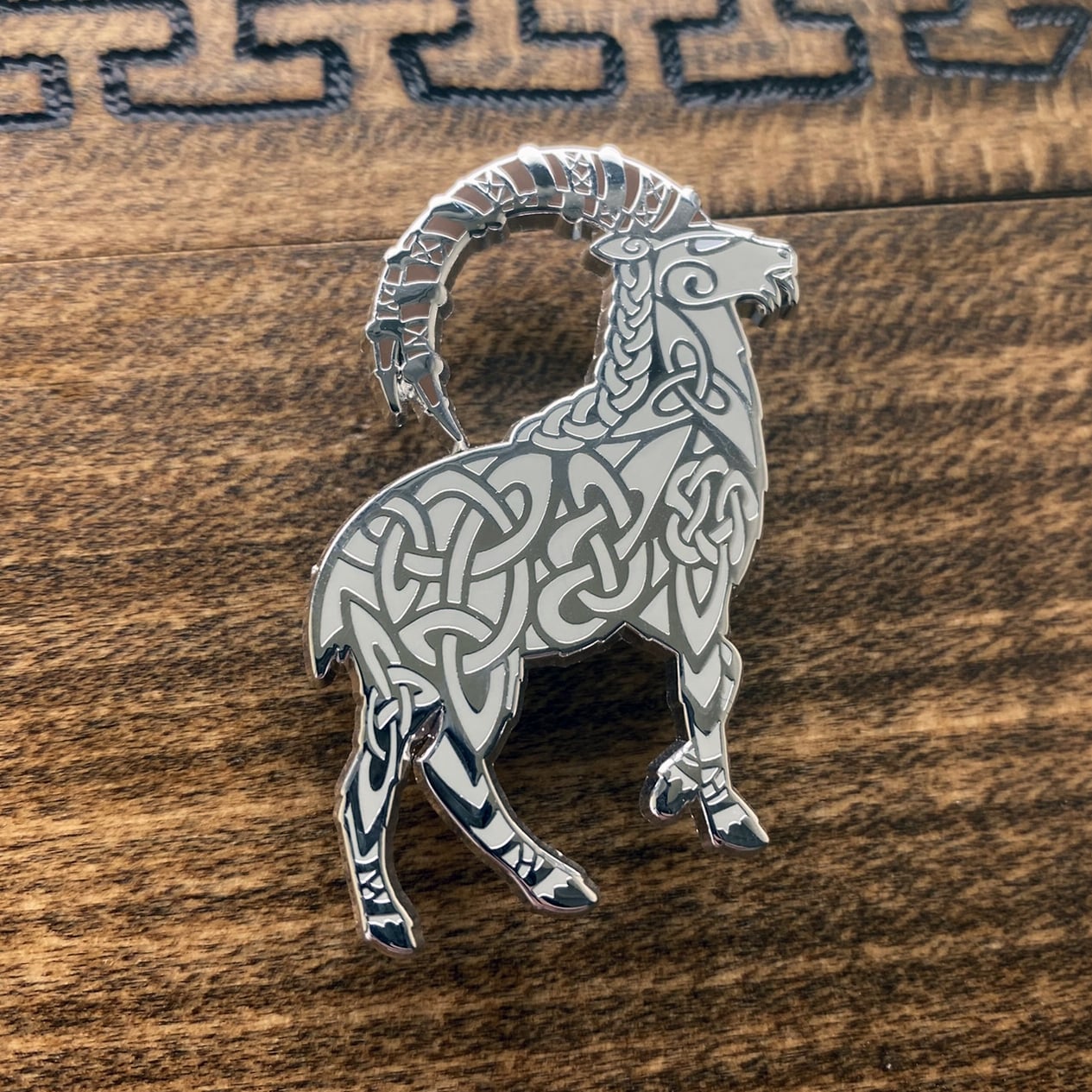 Norse god Thor, depicted as a goat enamel pin. The pin is silver plated and contains knotwork.