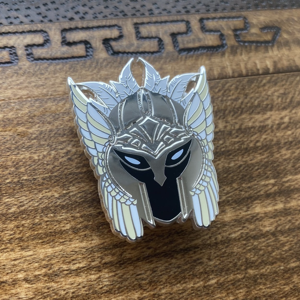 Silver-plated enamel pin of a valkyrie helmet, the Norse icons. Angle shows off the silver-plating.