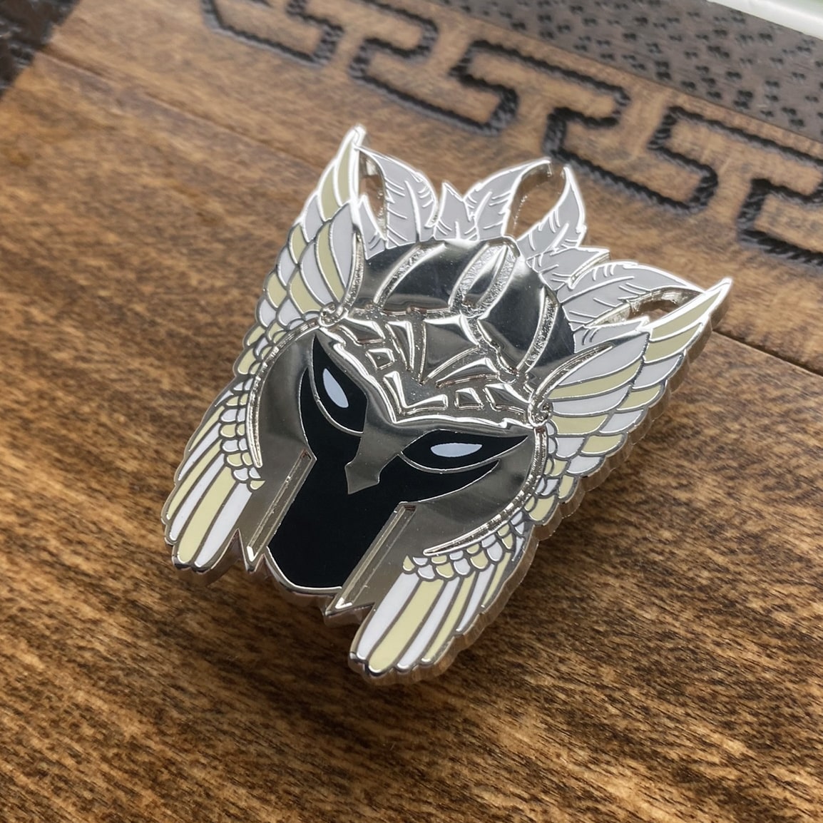 Silver-plated enamel pin of a valkyrie helmet, the Norse icons. Angle shows off the silver-plating.